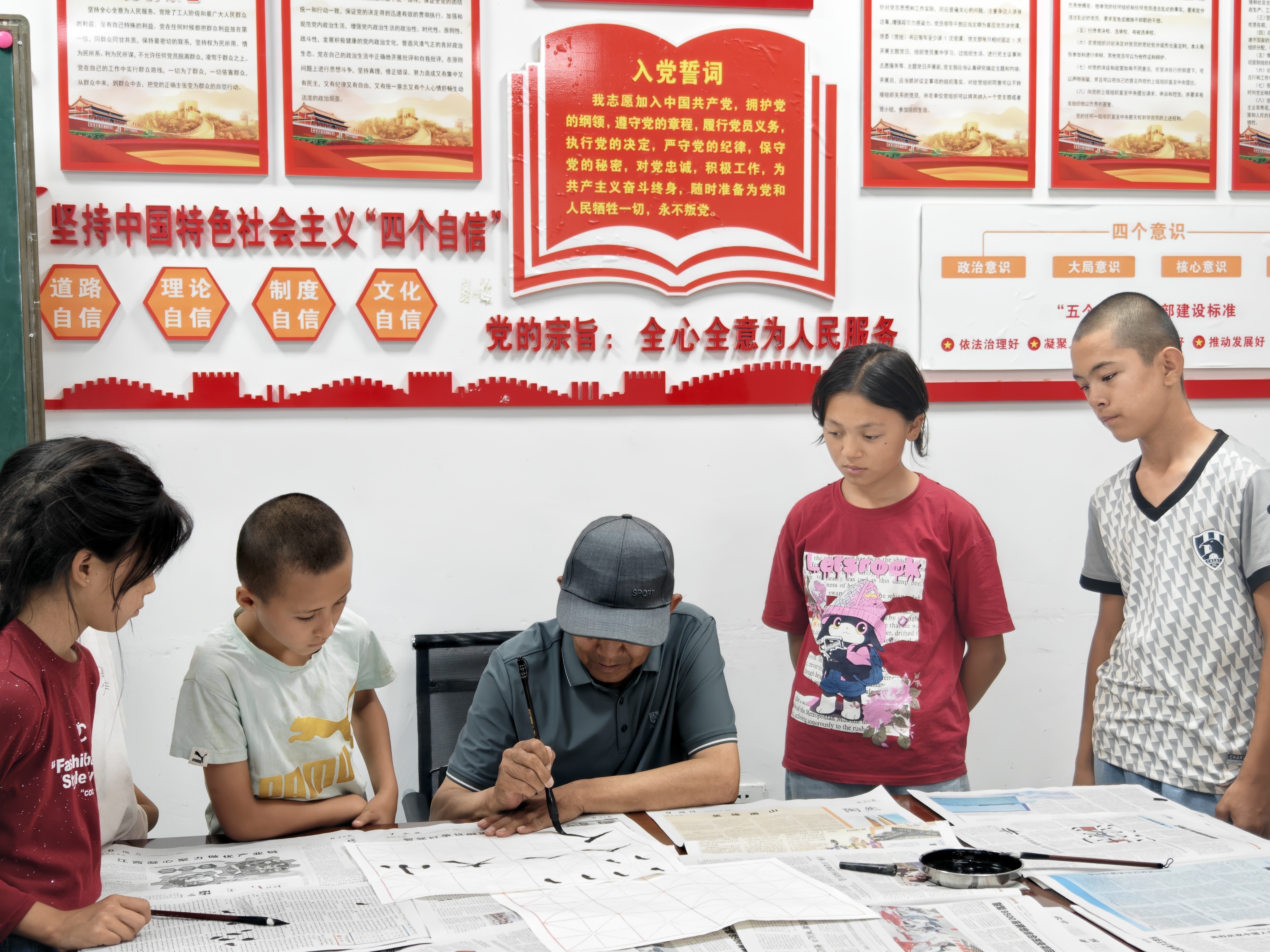 孩子们围在乡土文化能人身边学习书法.jpg 孩子们围在乡土文化能人身边学习书法.jpg